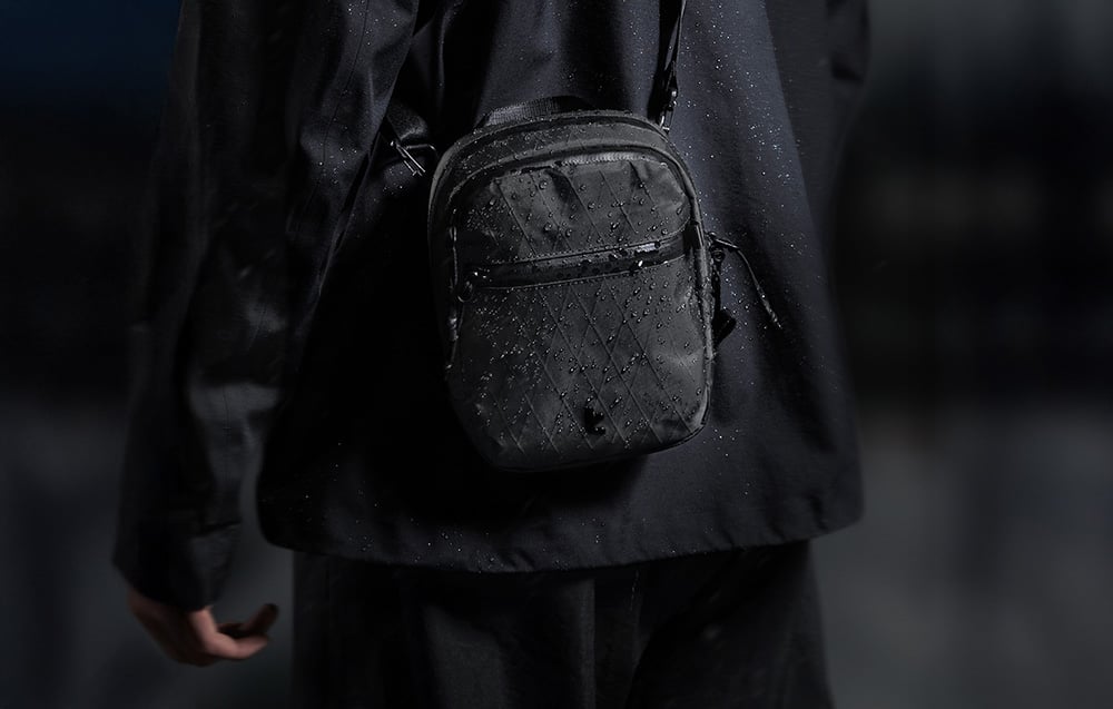 A person in a black jacket with a bag slung over the shoulder