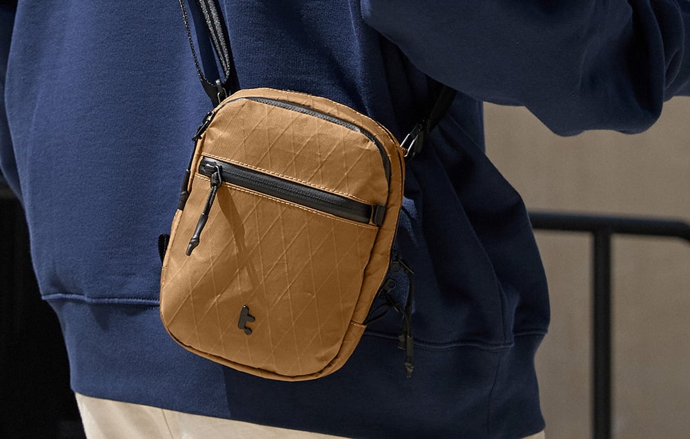 Brązowa torba przewieszona przez ramię osoby w granatowej bluzie