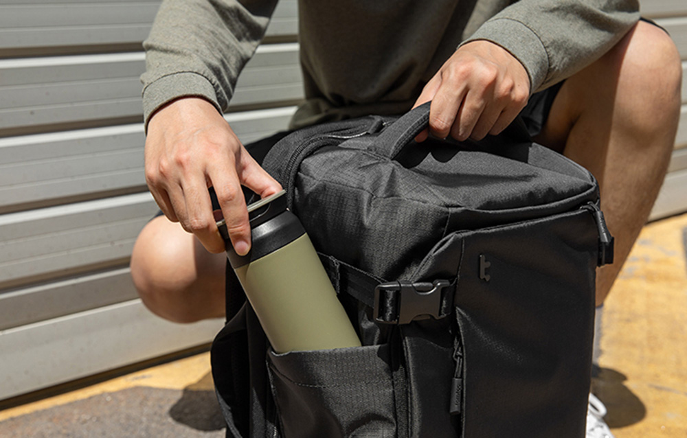 Mężyczyzna pakuje butelkę do dedykowanej kieszeni w plecaku