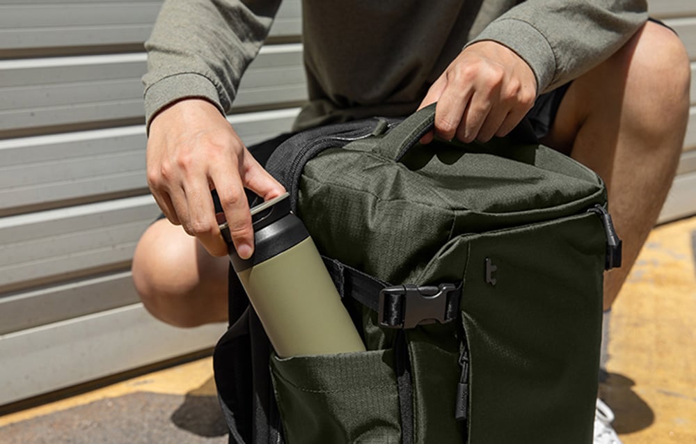 Mężczyzna pakuje do plecaka butelkę