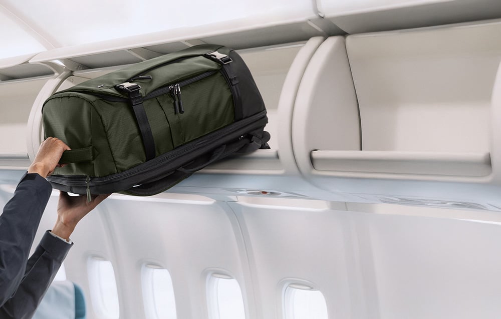 Mężczyzna wyjmuje z luku bagażowego plecak