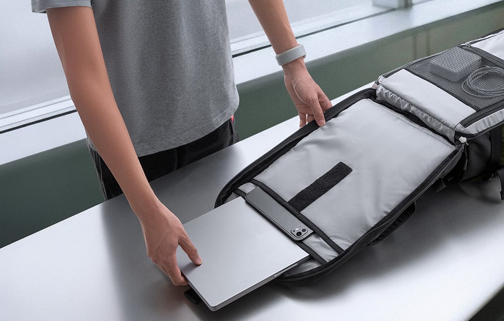 Mężczyzna wyjmuje laptopa z plecaka