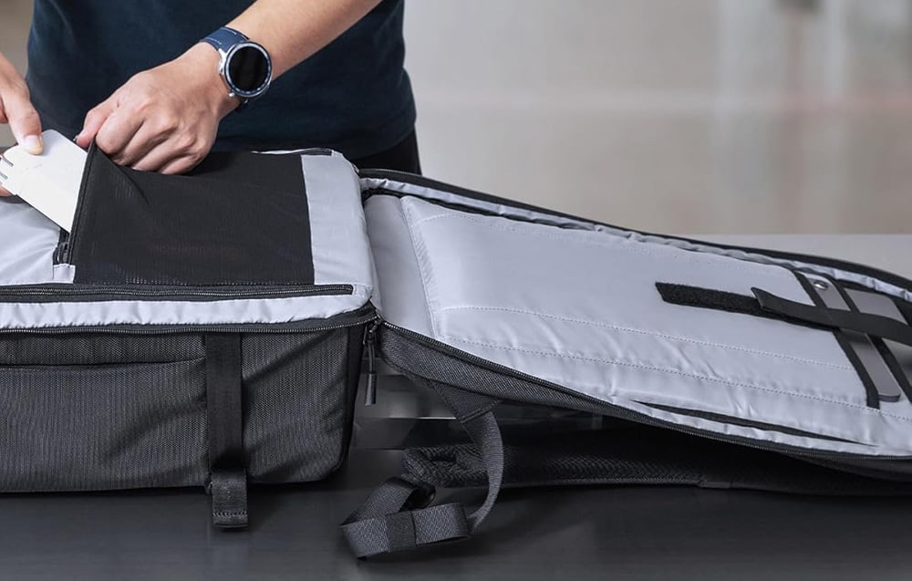 Ręka wkładająca powerbank do otwartej komory plecaka Tomtoc Navigator T67