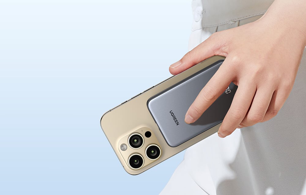 Dłoń trzymająca smartfon z przyczepionym magnetycznie powerbankiem Ugreen.