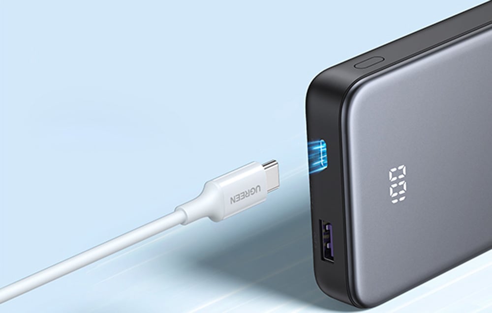 Kabel USB-C zbliżający się do podświetlonego portu wejściowego w powerbanku Ugreen.