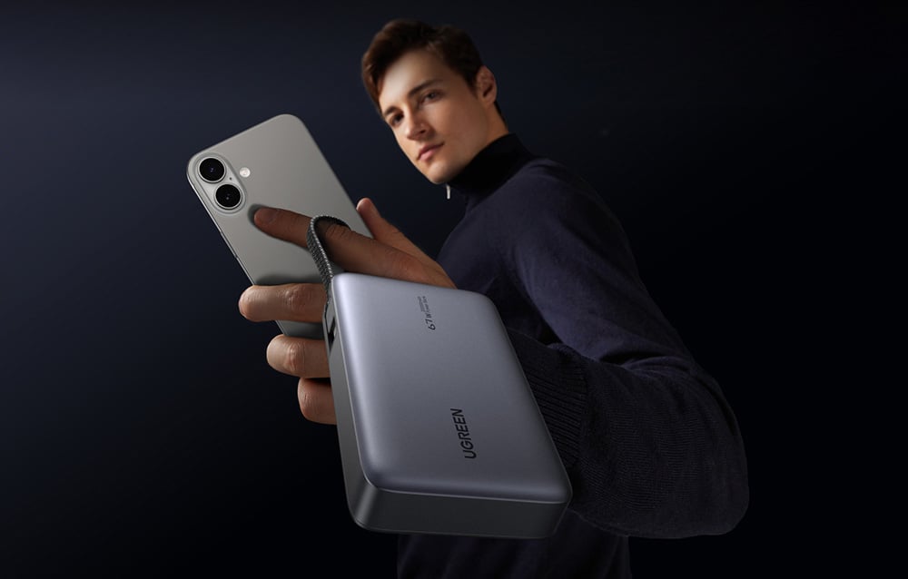 Mężczyzna trzymający w jednej dłoni powerbank Ugreen oraz smartfon, co podkreśla poręczność urządzenia.