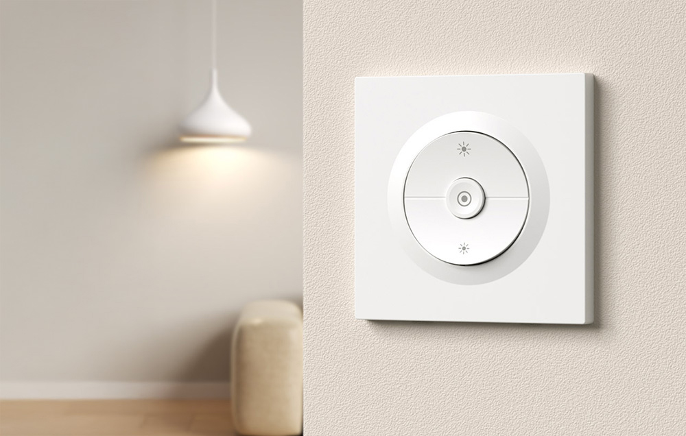 Przełącznik światła zamontowany na ścianie, w oddali zapalona lampa na suficie