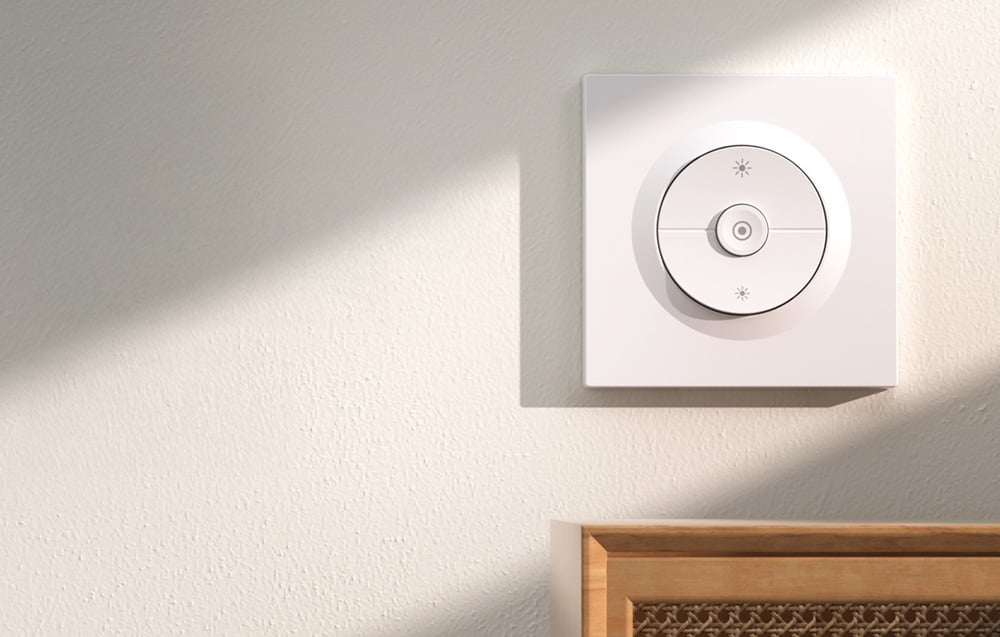 Przełącznik ścienny Sonoff na jasnej ścianie, pod którą znajduje się drewniana szafka