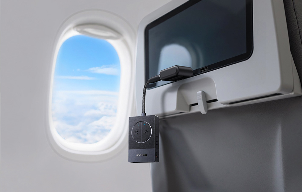 Czarny adapter audio podłączony do ekranu w samolocie, widok z okna samolotu w tle