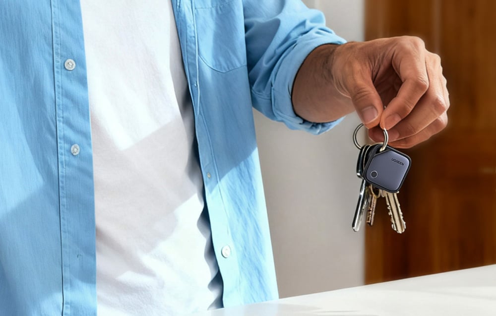 Osoba trzyma w dłoni pęk kluczy z przypiętym lokalizatorem UGREEN.
