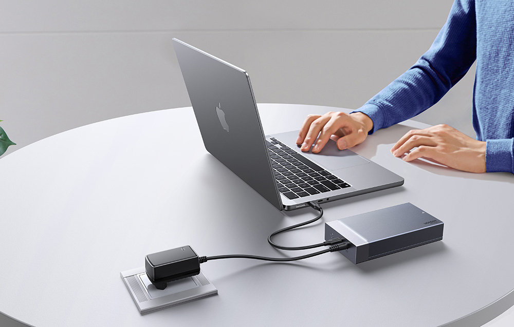 Laptop podłączony do obudowy dysku UGREEN, która jest zasilana z zewnętrznego adaptera.