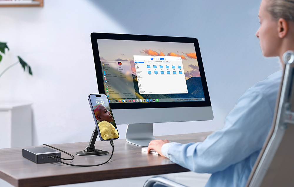 Osoba pracuje przy komputerze stacjonarnym z podłączonym smartfonem i obudową dysku UGREEN na biurku.