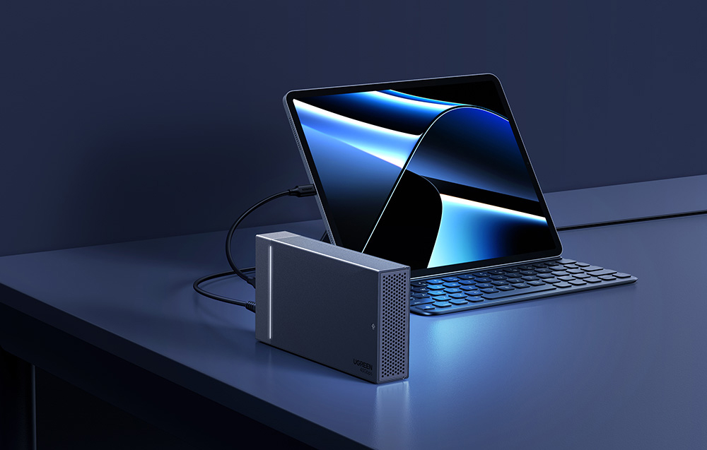 Tablet z klawiaturą podłączony przewodem do aluminiowej obudowy dysku UGREEN.