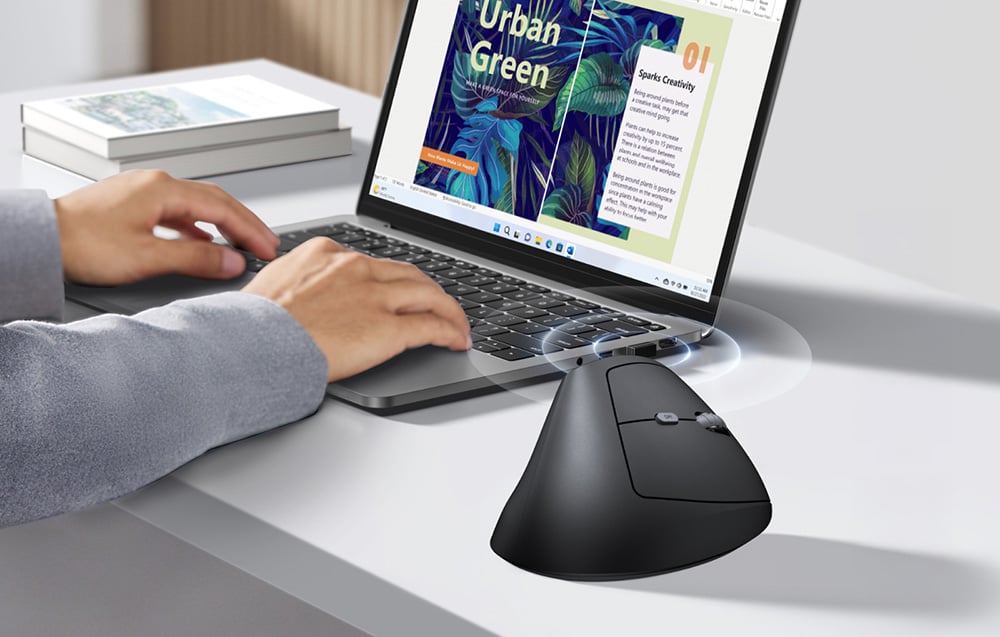 Laptop z otwartym programem graficznym i pionowa mysz UGREEN pokazana jako bezprzewodowo połączona z komputerem.