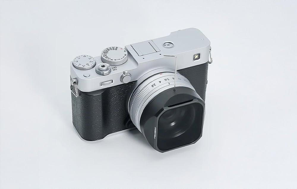 Retro-style camera with a mounted lens hood and Freewell filter, shown from above on a light background