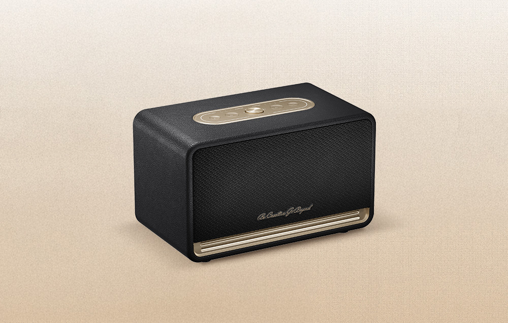 Czarny głośnik QCY ze złotymi elementami na beżowym tle