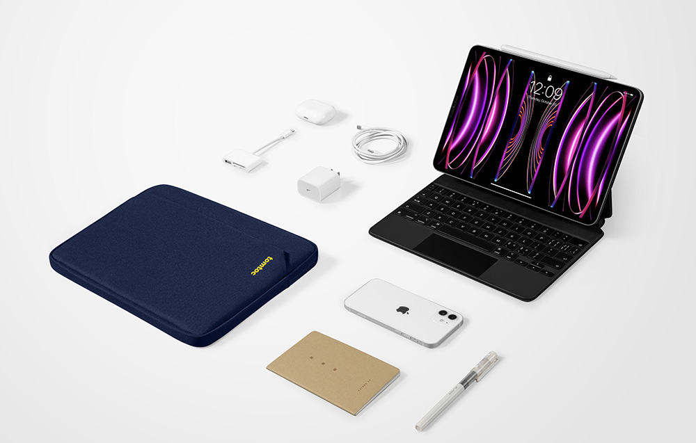 Zestaw akcesoriów na białym tle: granatowe etui tomtoc, iPad z klawiaturą, iPhone, AirPods, zasilacz, kable, notes i długopis