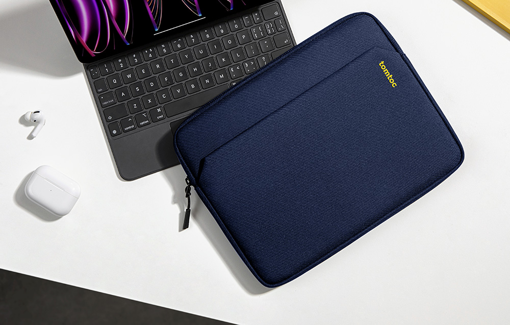 Granatowe etui tomtoc na biurku obok iPada z klawiaturą i słuchawek AirPods, widok z góry