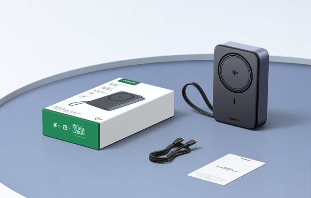 Szary powerbank magnetyczny Ugreen, czarny kabel, instrukcja obsługi, opakowanie, na niebieskiej, okrągłej powierzchni