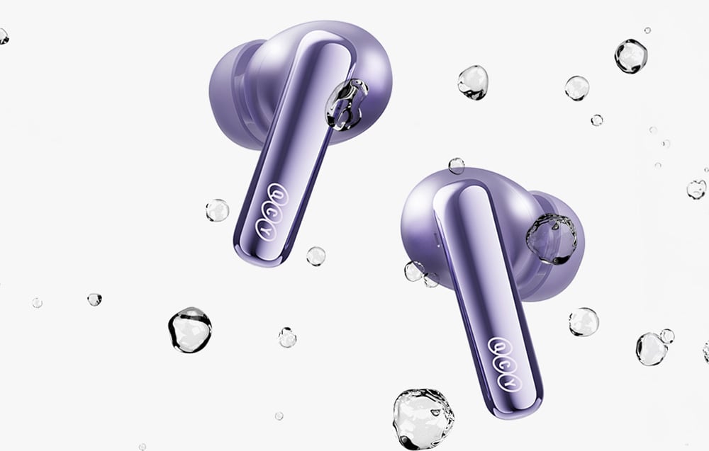 Dwie fioletowe słuchawki bezprzewodowe z logo QCY zanurzone w wodzie z bąbelkami powietrza