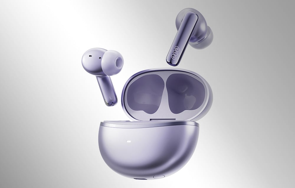 Dwie fioletowe słuchawki bezprzewodowe unoszące się nad otwartym etui ładującym