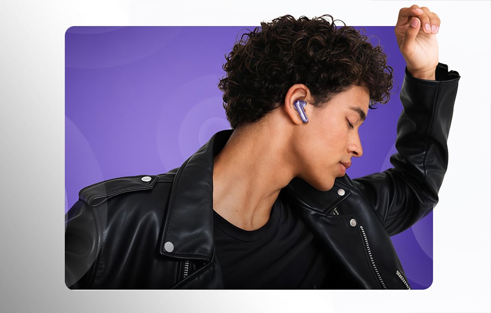 Mężczyzna w czarnej skórzanej kurtce tańczy, mając w uchu fioletową słuchawkę bezprzewodową