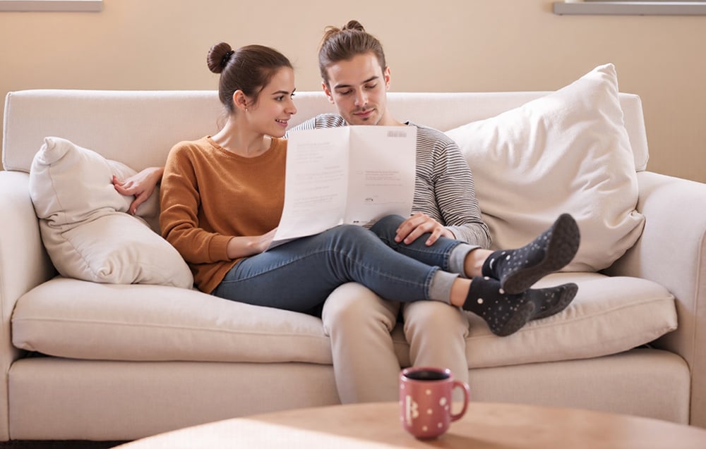 Chłopak i dziewczyna siedzą na kanapie i czytają kartkę