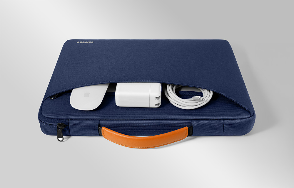 Granatowe etui na laptopa z otwartą przednią kieszenią zawierającą myszkę, zasilacz i zwinięty biały kabel