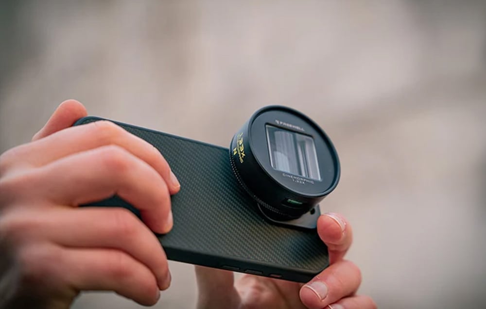 Close-up of hands holding a smartphone with a black anamorphic lens featuring rectangular glass.