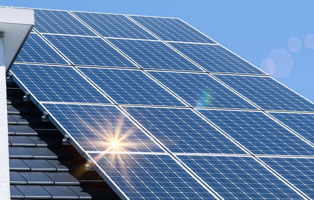Detail na fotovoltaické panely na střeše, na kterých se odrážejí sluneční paprsky