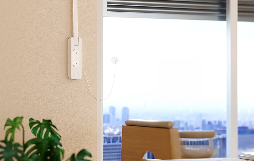 Intelligent roller shade motor Meross on the wall next to a large window with a view of the city skyline