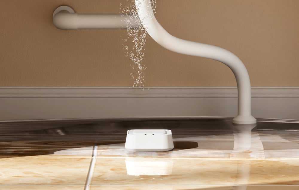 Intelligent water leak sensor MEROSS placed on the floor under a pipe leaking water