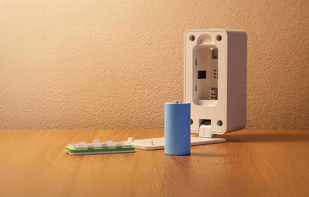 Intelligent presence sensor lying on a wooden table with the battery removed