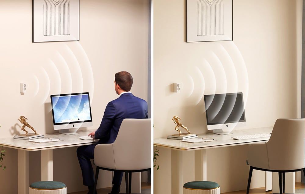 A man sitting at a desk working on a computer, next to a home office workspace