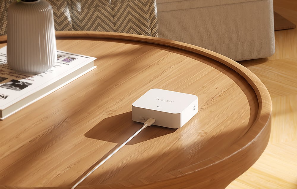 Intelligente Wi-Fi-Gateway MEROSS, angeschlossen an ein Kabel, liegt auf einem Holztisch
