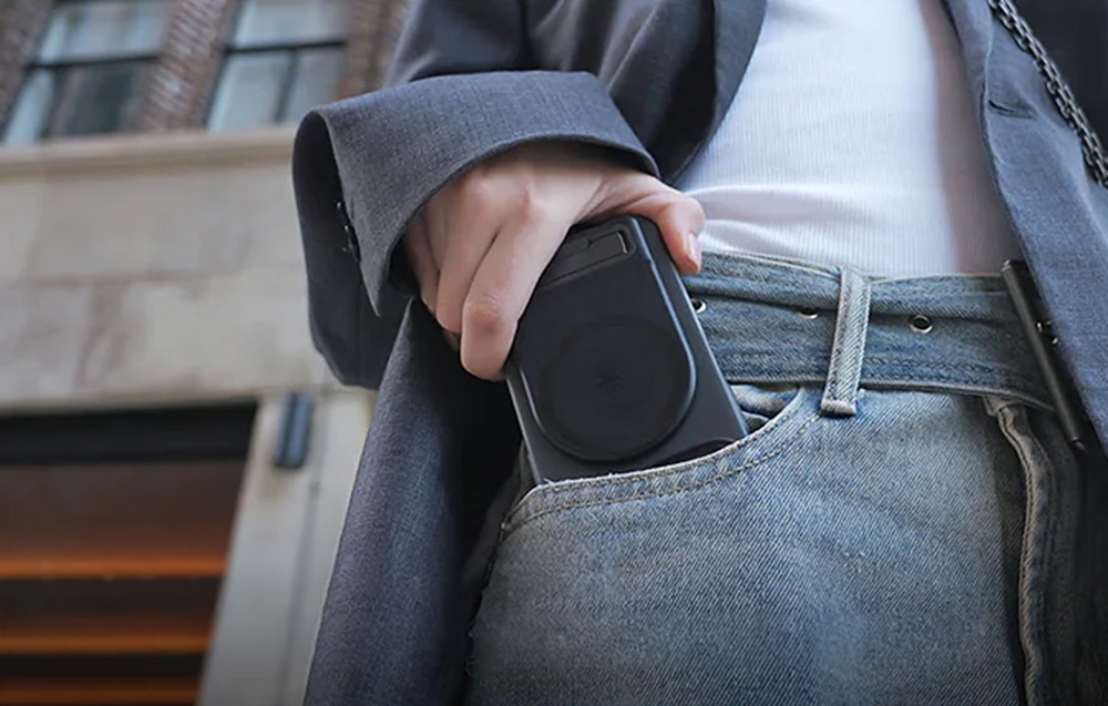 A person putting a smartphone with a grip into the front pocket of jeans