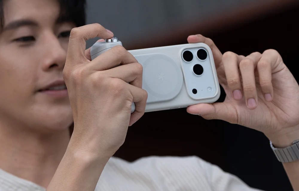 A person holding a smartphone with a grip and photographing horizontally