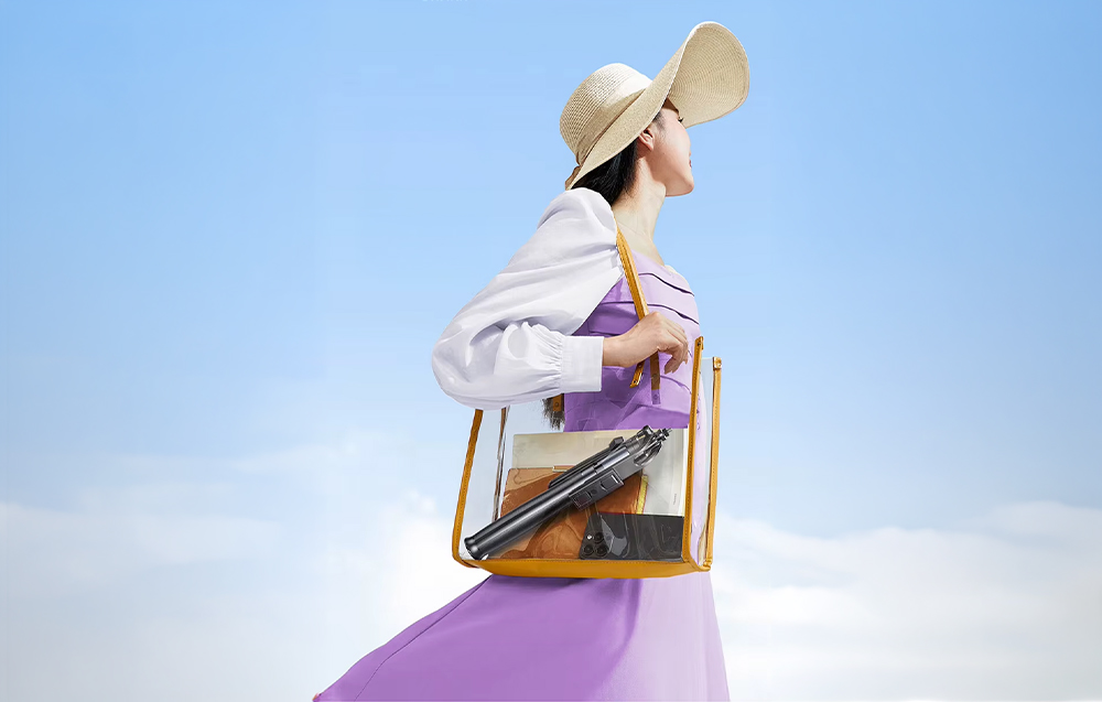 Woman in a hat carrying a transparent bag containing a folded tripod and phone