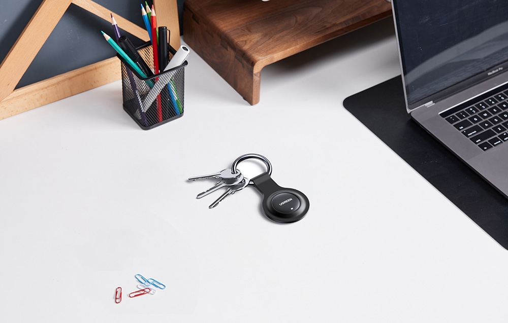 Chei cu localizator pe birou lângă laptop și organizator cu pixuri