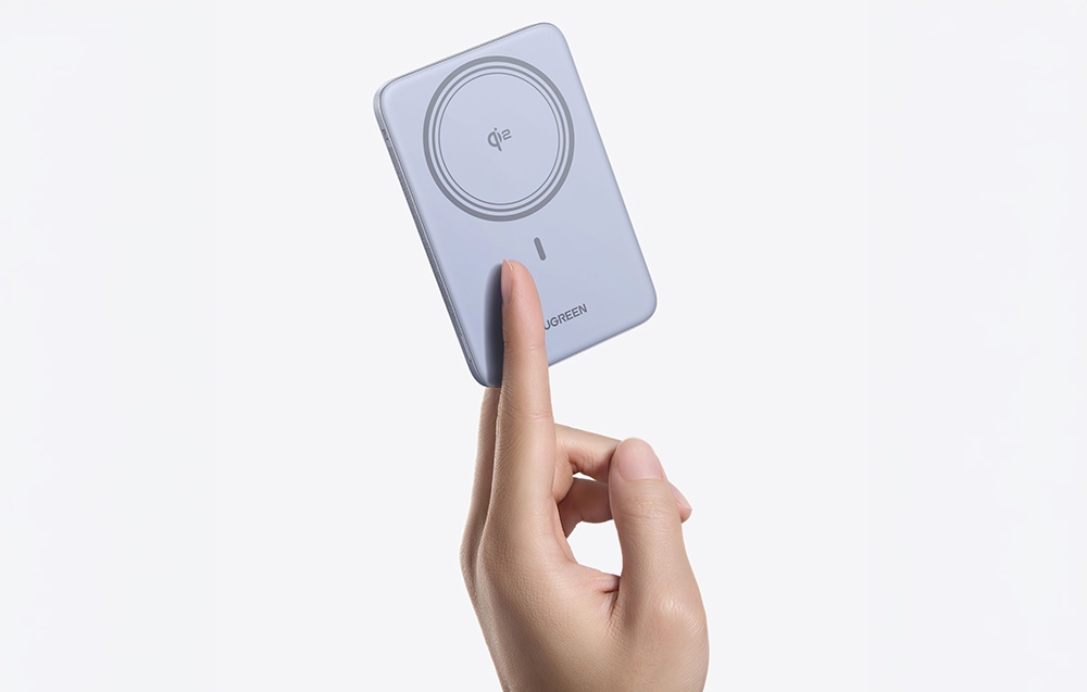 A hand holding the Ugreen power bank against a light background