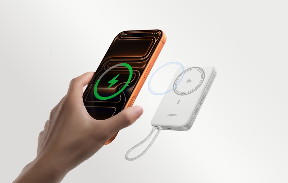 An orange smartphone being placed against a white power bank with wireless charging