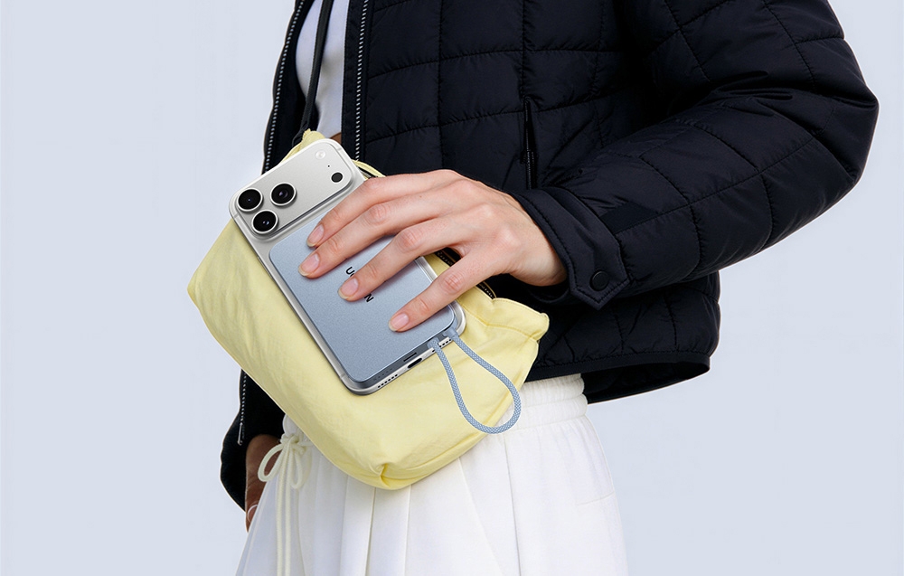 Woman holding a smartphone connected to the power bank and a handbag