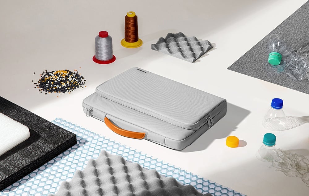 The tomtoc bag lying among production materials such as plastic bottles, threads, foam, and granules.