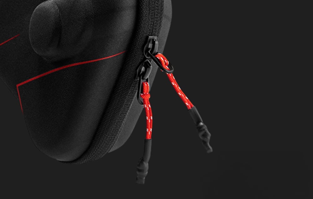 Close-up of the double black zipper of the case with ergonomic red and black pull strings.