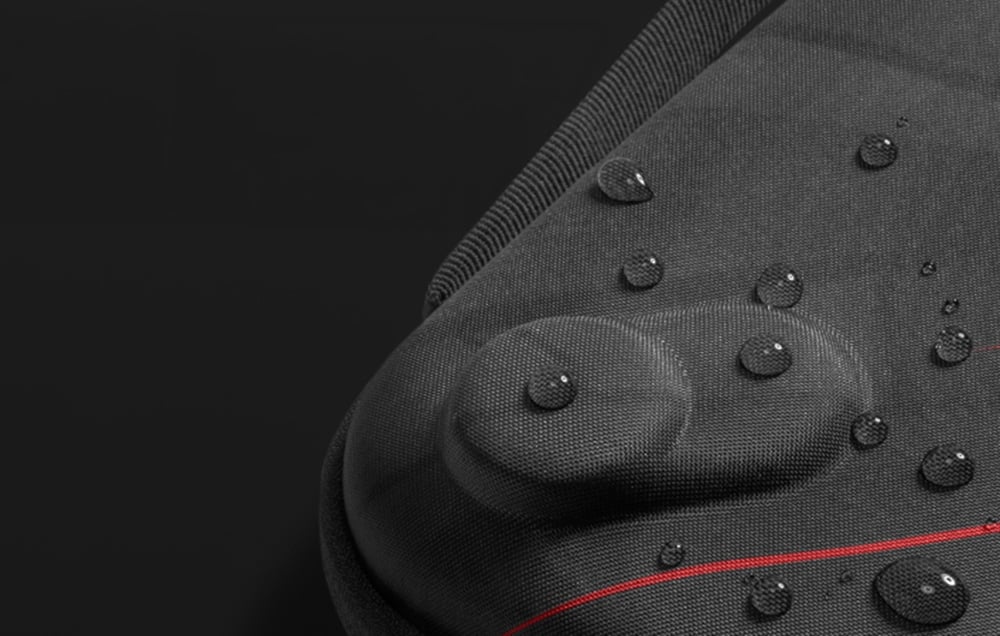 Water droplets running down the waterproof surface of a black fabric case.