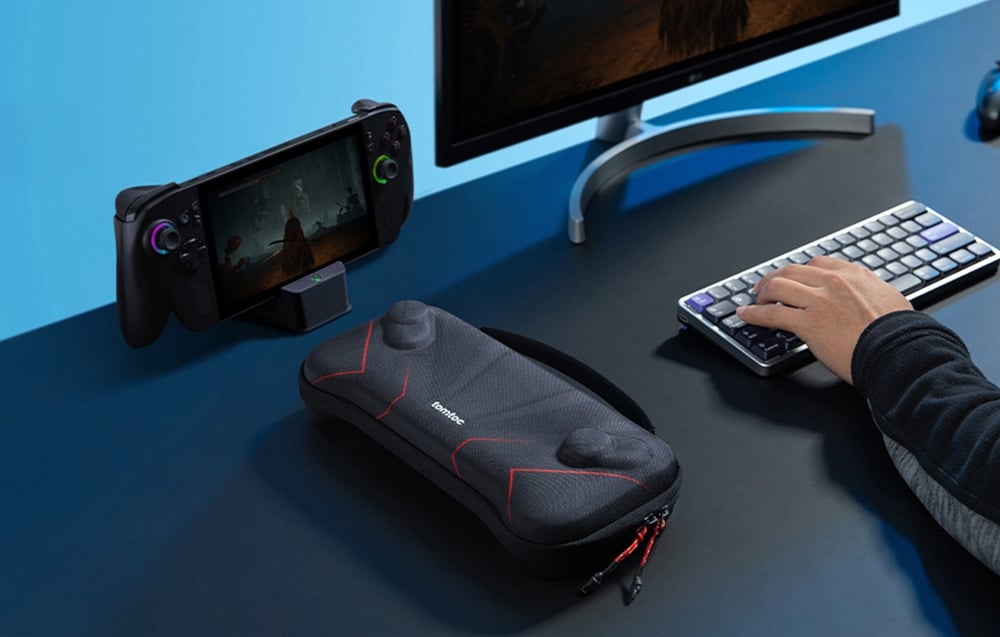 The tomtoc case lying on a gamer’s desk next to a computer keyboard and a console in a docking station.