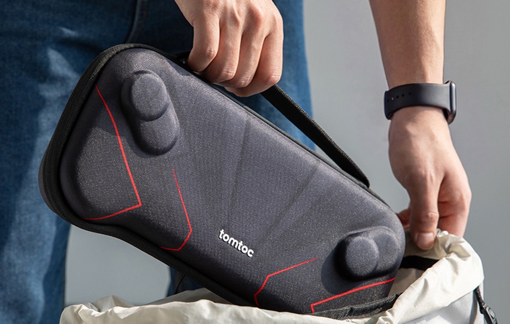 A man holding a black case by the handy strap and putting it into an open backpack.