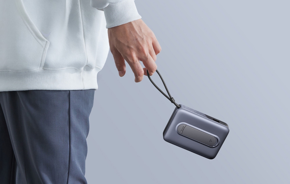 Osoba trzyma kompaktowy powerbank UGREEN za dołączoną pętlę do przenoszenia.