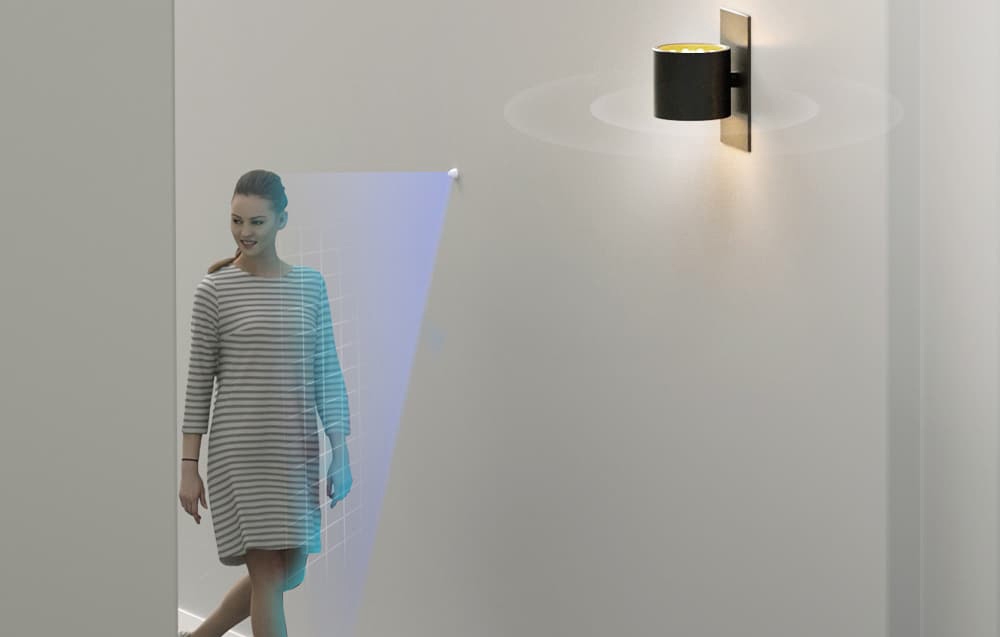 Kobieta przechodzi obok czujnika, po czym zapala się lampa