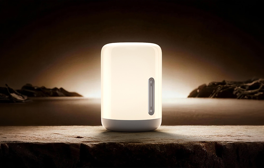 Turned on night lamp placed on a raw stone surface against a dark landscape background